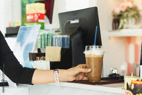 Woman holding plastic takeaway cup of iced coffee in cafe.