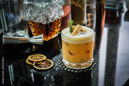 A glass of signature cocktail decorated with Crispy Coconut Roll ( Thai dessert ) ,black sesame, and fresh Rosemary in Bangkok Thailand