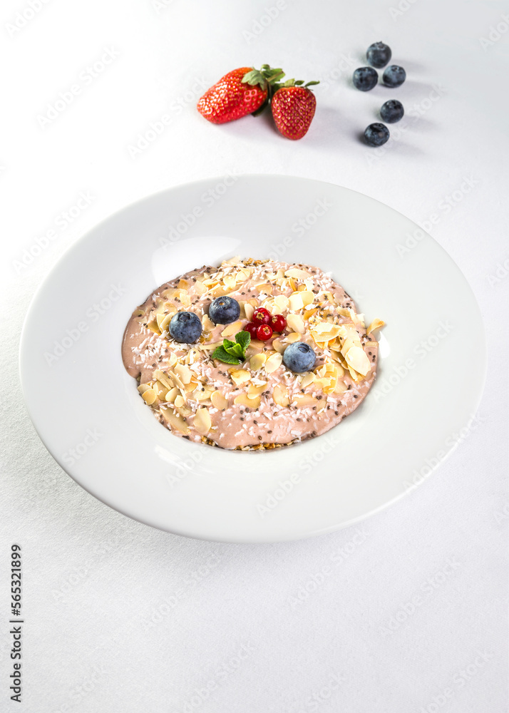 Oatmeal with almonds, blueberries and strawberries in a white plate on a white background Oatmeal with almonds, blueberries and strawberries in a white plate on a white background