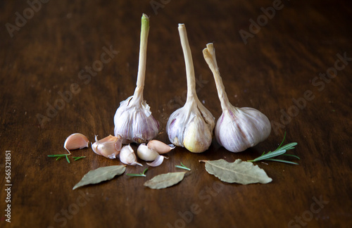 Garlic cloves on a wooden background with laurel leaves and rosemary, aesthetic herbs