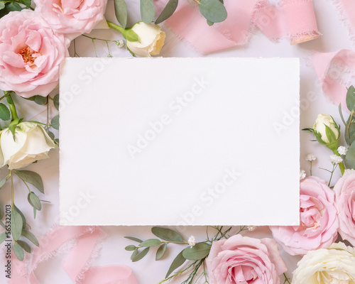 Fototapeta Naklejka Na Ścianę i Meble -  Blank card between pink roses and pink silk ribbons on marble top view, wedding mockup