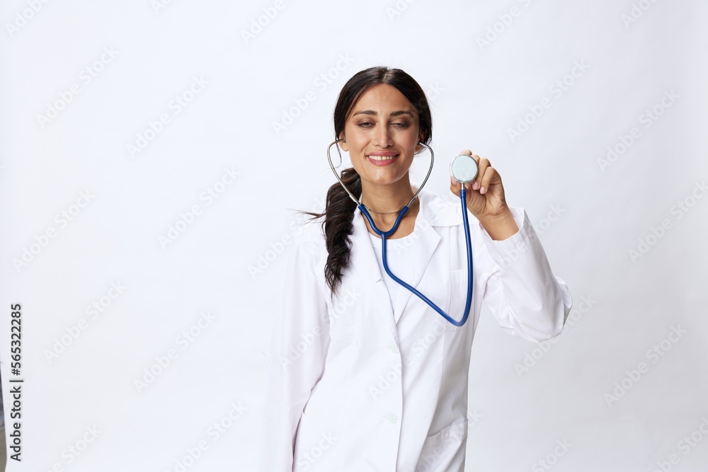 Woman doctor with stethoscope in hand in medical gown on white nurse background, consequences of covid-19, noise in lungs, concept of health and science Woman doctor with stethoscope in hand in medical gown on white nurse background, consequences of covid-19, noise in lungs, concept of health and science