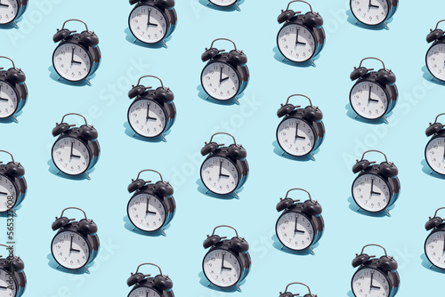 Seamless pattern of black retro alarm clocks  show 3 o'clock and one shows 2. Changing clock from summer time to winter time. Shifting the clock hands back in autumn.