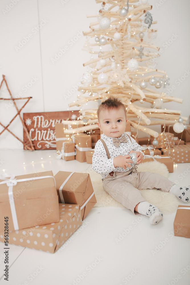 little boy near a wooden Christmas tree. New Year's photo zone with a wooden Christmas tree and craft gifts. family New Year's photo. handmade Christmas tree. little son in beige clothes little boy near a wooden Christmas tree. New Year's photo zone with a wooden Christmas tree and craft gifts. family New Year's photo. handmade Christmas tree. little son in beige clothes