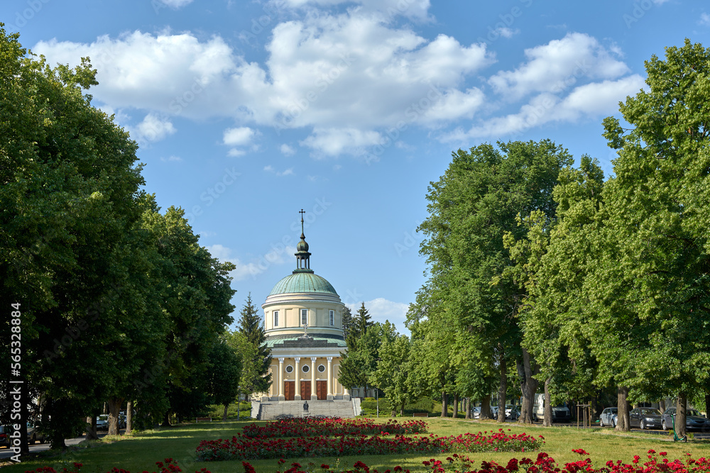 Square with flower beds, trees and facade of the catholic church in the city of Poznan