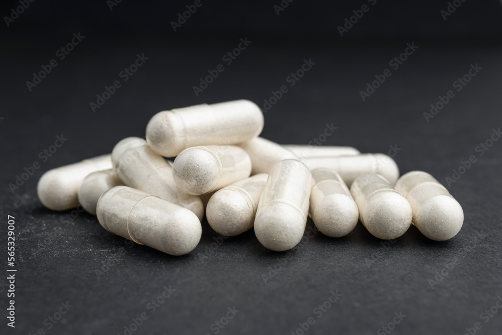 White medical capsules or pills for treatment on dark background, medicine and healthcare concept, close-up view White medical capsules or pills for treatment on dark background, medicine and healthcare concept, close-up view