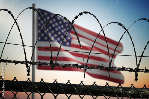 USA flag behind barbed wire fence. Illegal immigration and security in United States.