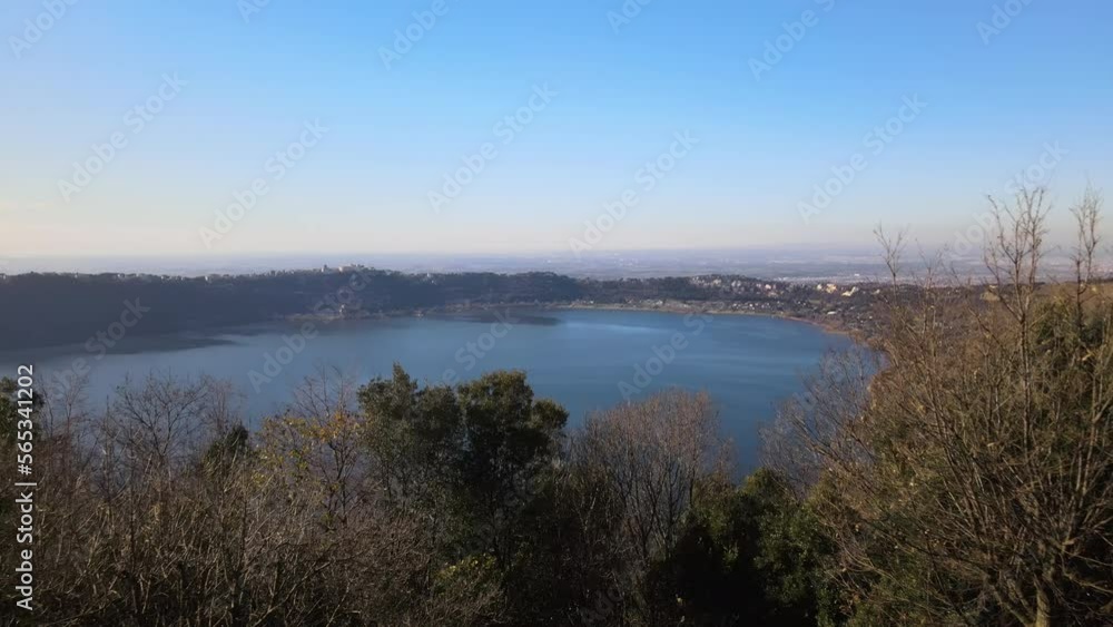 Volcanic Italian Albano lake with sunlights reflections on water surface and mountains hills with different historical cities and villages called Castelli Romani. Panoramic view of picturesque Volcanic Italian Albano lake with sunlights reflections on water surface and mountains hills with different historical cities and villages called Castelli Romani. Panoramic view of picturesque