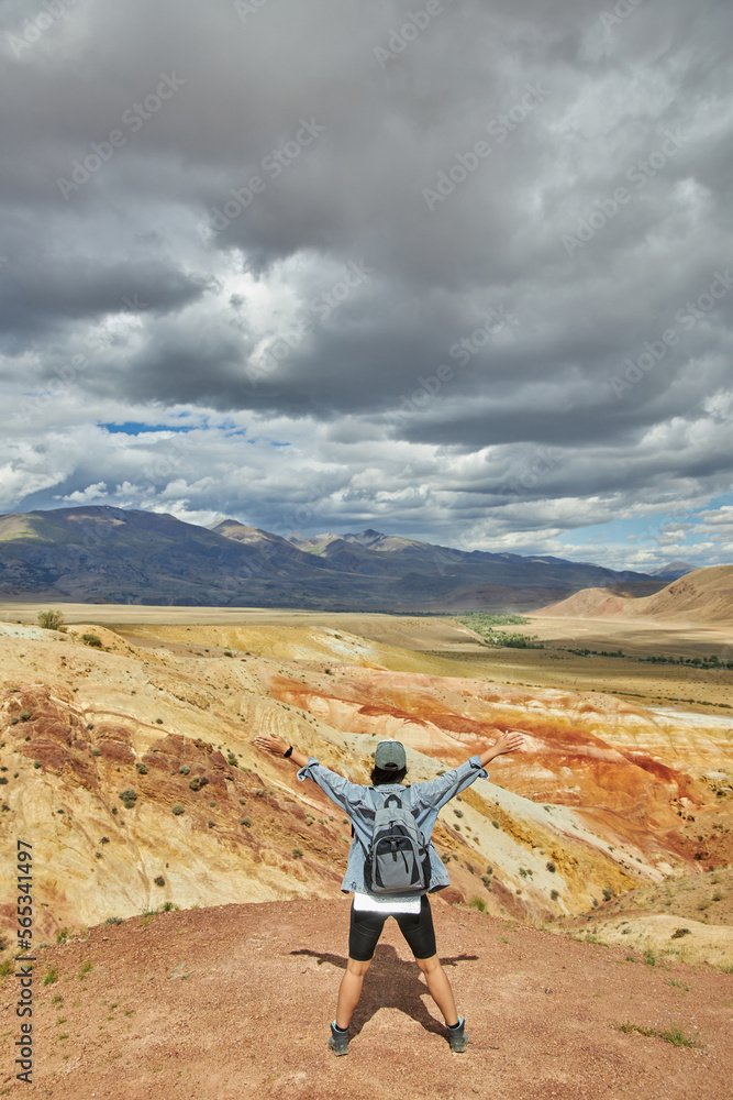 woman tourist spread his arms in an embrace, against backdrop of landscape. Sights of Russia, Siberia and Altai Republic, mars field. Tourism, travel and adventure. Kosh-agach, Chagan-Uzun