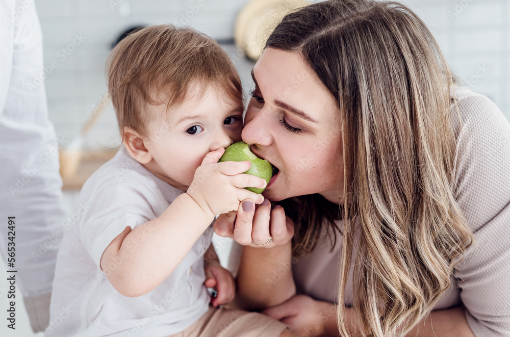 Mom and son bite one apple at the same time Mom and son bite one apple at the same time