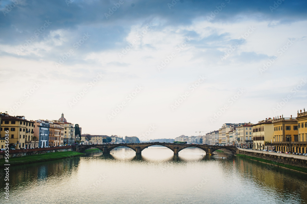 View of the Arno River in Italy and the historic bridge with the reflection of beautiful colorful houses in the water