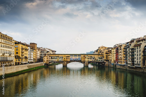 View of the Arno River in Italy and the historic Ponto Vecchio bridge with reflection in the water