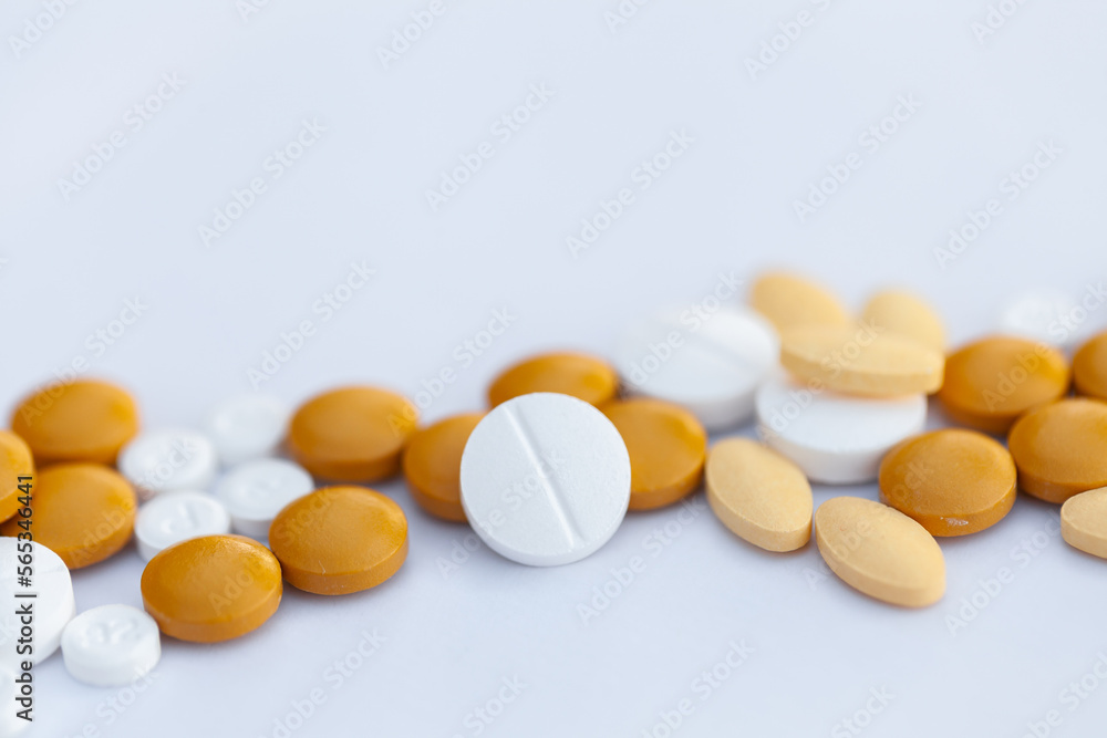 Orange and white medical tablets scattered on white with copy space Orange and white medical tablets scattered on white with copy space