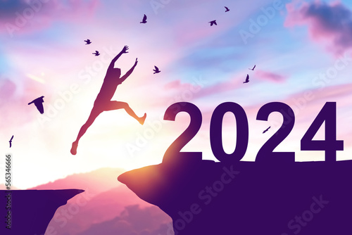 Silhouette man jumping between cliff to 2024 and birds flying at top of mountain. Freedom challenge and travel adventure holiday concept.