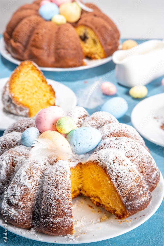 Traditional cake for Easter. Chocolate and vanilla Easter round cake with chocolate and sugar powder sprinkles, colorful Easter eggs, spring flowers, on a blue background copy space Traditional cake for Easter. Chocolate and vanilla Easter round cake with chocolate and sugar powder sprinkles, colorful Easter eggs, spring flowers, on a blue background copy space