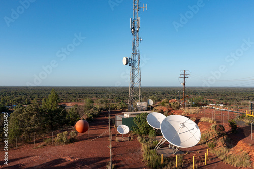 Aerial view of satellite dishes at the base of a communications tower in a barren outback setting photo