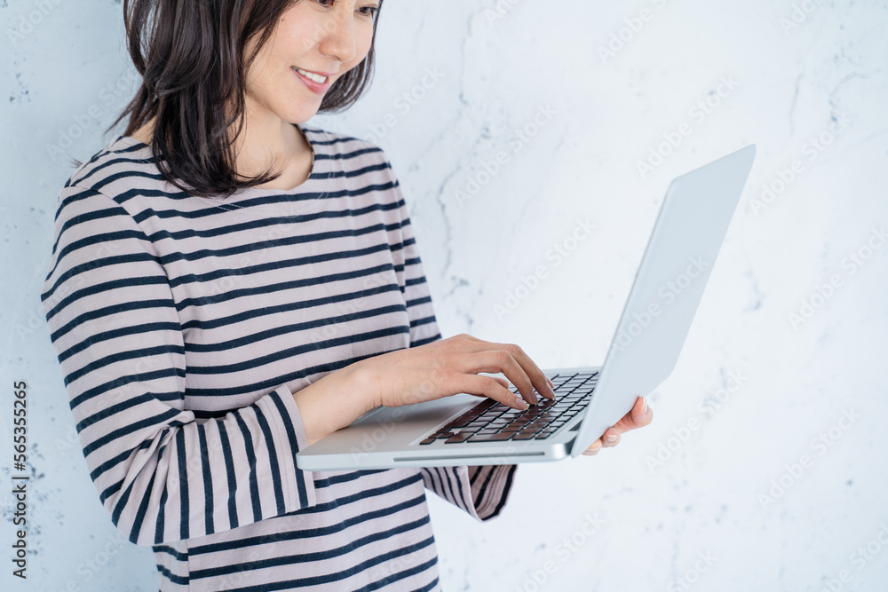 Naklejka premium 明るいリビングでノートパソコン作業でする30代女性の手元