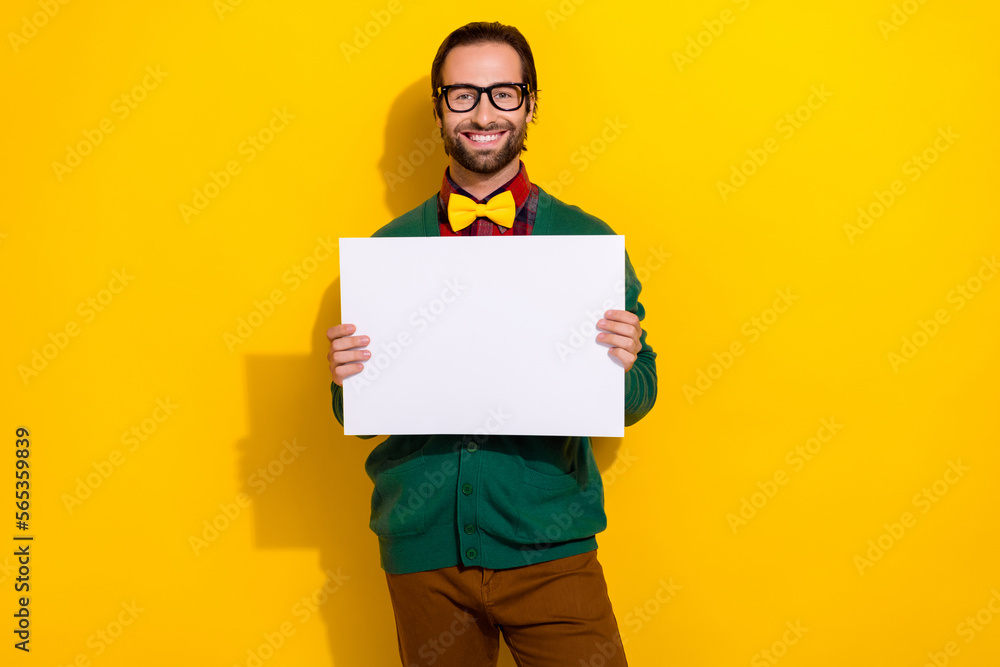 Portrait of positive classy man toothy smile arms hold empty space blank isolated on yellow color background Portrait of positive classy man toothy smile arms hold empty space blank isolated on yellow color background