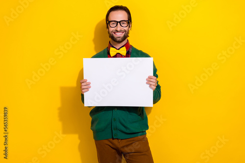 Portrait of positive classy man toothy smile arms hold empty space blank isolated on yellow color background