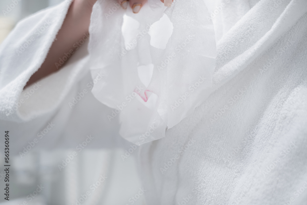 Woman with a sheet mask in her hands in the bathroom before applying it to her face Woman with a sheet mask in her hands in the bathroom before applying it to her face