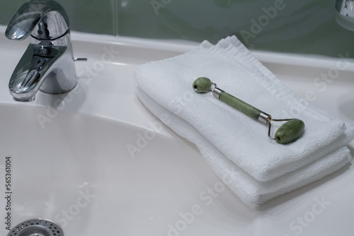 Stack of fresh towels and face roller on countertop in bathroom