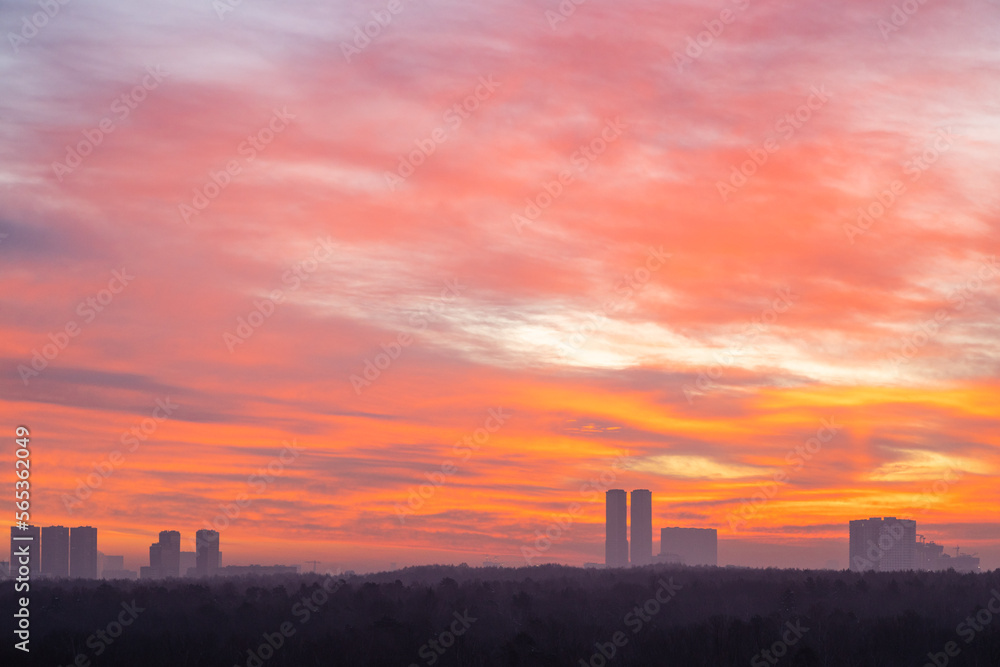 red and orange sky over city park and towers at cold dawn