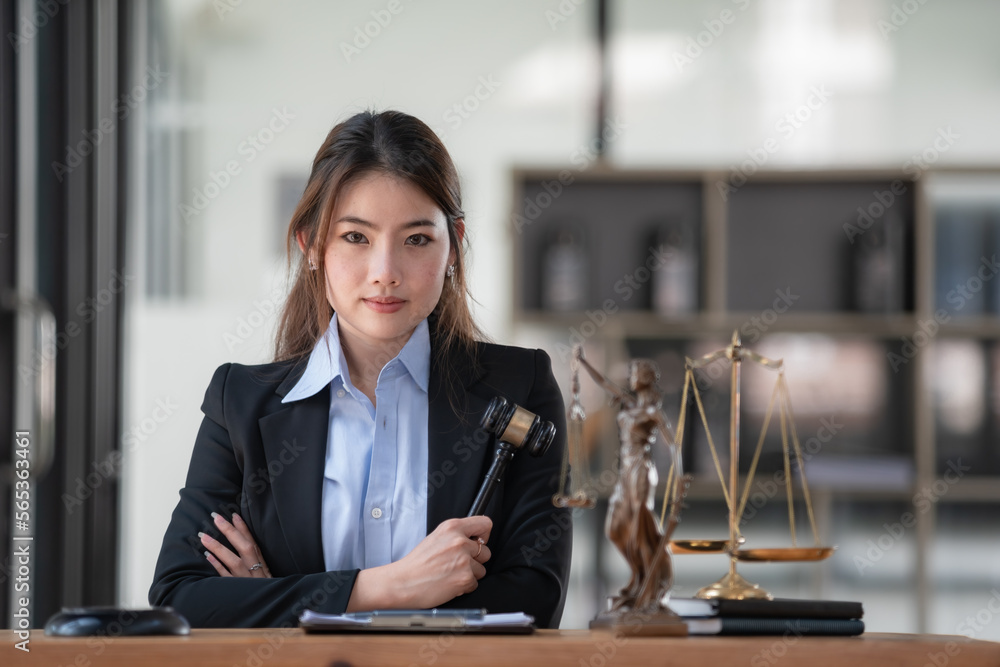 Portrait of a young female Lawyer or attorney working in the office and holding a wooden gavel, smiling, and looking at the camera. Portrait of a young female Lawyer or attorney working in the office and holding a wooden gavel, smiling, and looking at the camera.