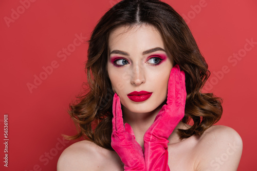 portrait of young woman with magenta color eye shadow and gloves posing isolated on pink.