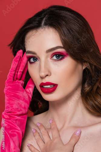 young woman with magenta color eye shadow and bright glove posing isolated on pink.