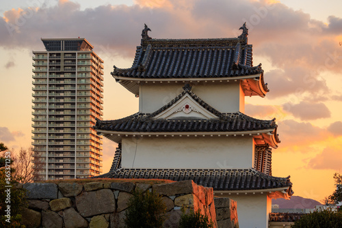 Sunset over watchtower in Japanese castle and modern high rise apartment building