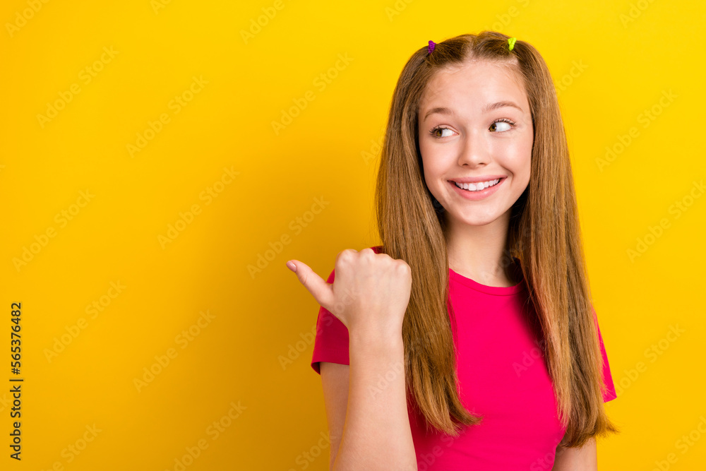 Portrait of positive toothy beaming girl with long hairdo dressed pink top look indicating empty space isolated on yellow color background Portrait of positive toothy beaming girl with long hairdo dressed pink top look indicating empty space isolated on yellow color background