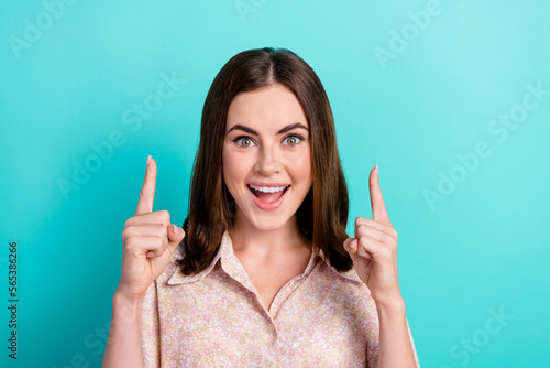 Photo portrait of cute young woman excited point up empty space dressed stylish smart casual look isolated on aquamarine color background