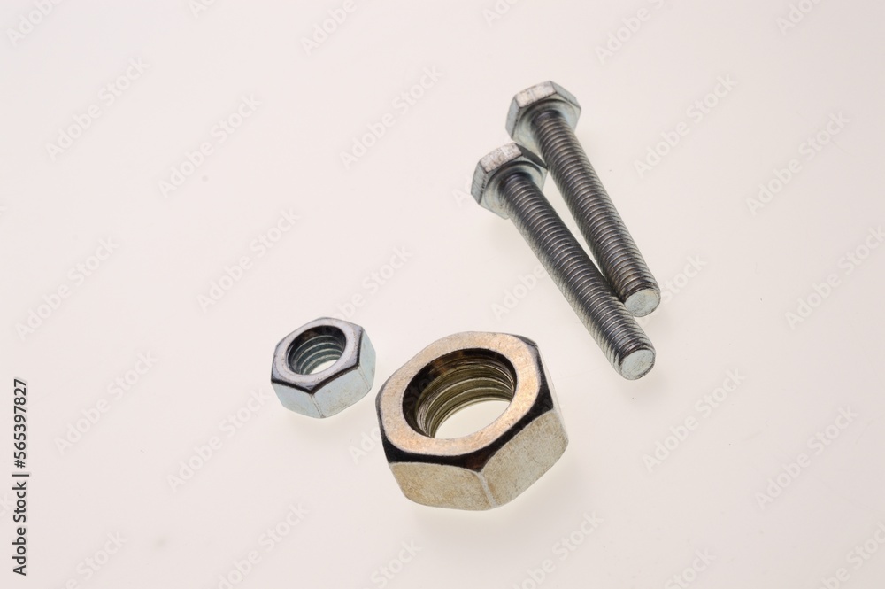 New, chrome-plated bolts and nuts of different sizes lie on a white background. Close-up New, chrome-plated bolts and nuts of different sizes lie on a white background. Close-up