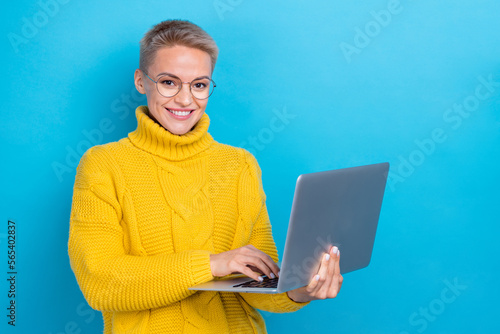 Photo of intelligent adorable lady wear stylish yellow winter sweater use netbook near empty space isolated on blue color background