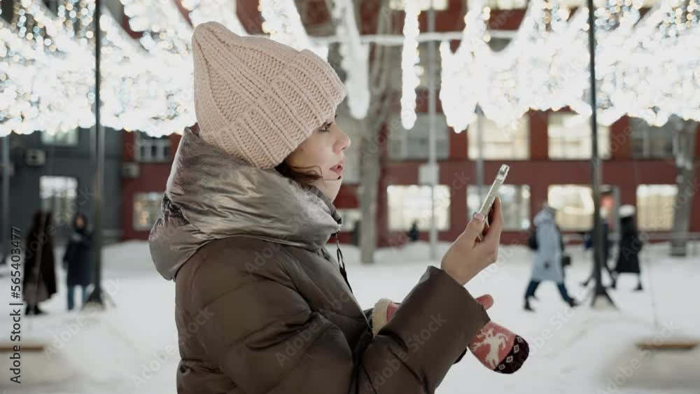Young woman with mobile phone in the winter city at christmas time Young woman with mobile phone in the winter city at christmas time