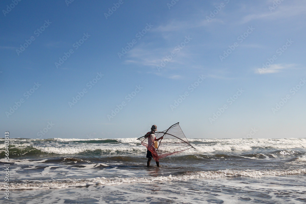Naklejka premium Yogyajarta, Indonesia - April 19 2020: a fisherman who is looking for fish on the shoreline