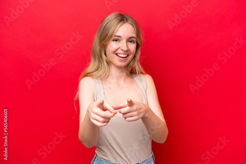 Young English woman isolated on red background surprised and pointing front