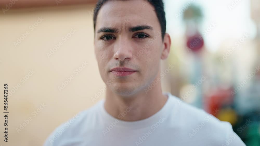 Young hispanic man standing with serious expression at street Young hispanic man standing with serious expression at street