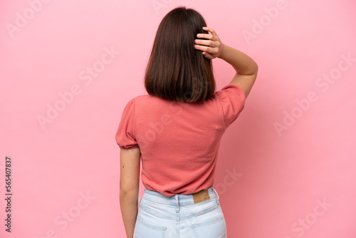 Young Ukrainian woman isolated on pink background in back position and thinking