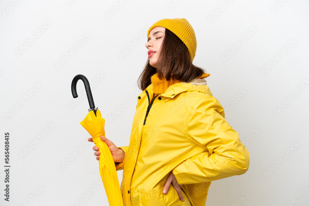 Young Ukrainian woman with rainproof coat and umbrella isolated on white background suffering from backache for having made an effort Young Ukrainian woman with rainproof coat and umbrella isolated on white background suffering from backache for having made an effort