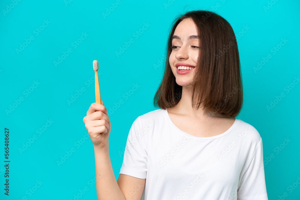 Young Ukrainian woman brushing teeth isolated on blue background with happy expression Young Ukrainian woman brushing teeth isolated on blue background with happy expression