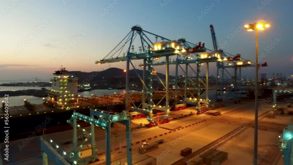 Drone view of container loading and giant cranes in port at sunset