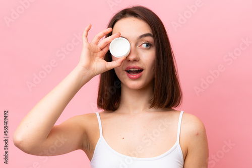 Young Ukrainian woman isolated on pink background with moisturizer