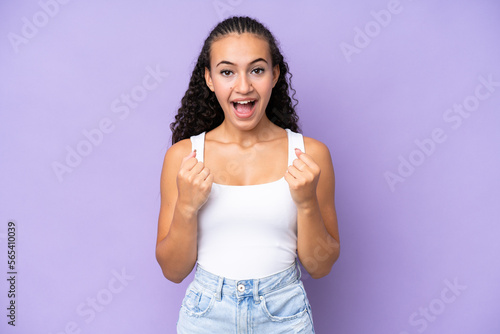 Young woman isolated on purple background celebrating a victory in winner position