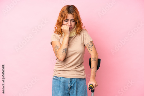 Young caucasian woman wearing neck brace isolated on pink background having doubts