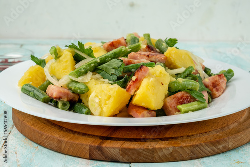 Closeup potato salad with green beans, bacon. Served in a white plate, Belgian or Liege salad.
