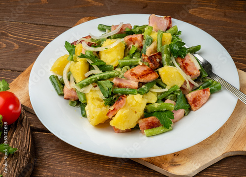 Bright and tasty traditional Belgian salad of potato greens and beans on a wooden background.