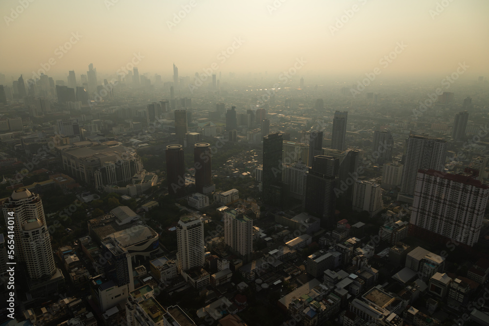 Panoramic view of the skyline of Bangkok, Thailand, at sunset, with its skyscrapers, plunged in pollution, from the observation deck of the Baiyoke Tower II