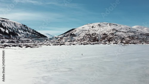 Aerial view of man walking on frozen lake. Range of mountains, frozen lake, trees. Wide angle. Turkey Adiyaman Celikhan Cat Baraji photo