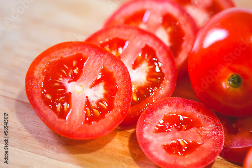 Tomates sobre uma tábua de madeira em fotografia macro. Tomates cortados e tomates inteiros. Alimento, vegetal, orgânico. photo